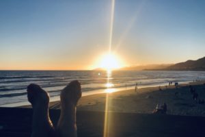 Katarina Stoltz Life Coaching and Psychotherapy with feet up at sunset on the beach representing feeling less stressed