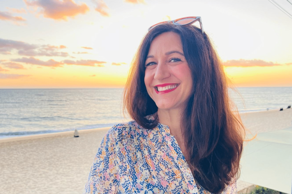 Life coach Katarina Stoltz smiling in front of the sea at sunset in Portugal