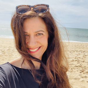 Life coach Katarina Stoltz smiling on the beach in Faro, Portugal following a retreat with Michaela Boehm.