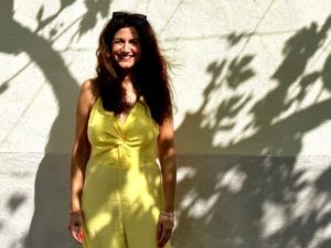 Life coach Katarina Stoltz in Mallorca wearing a yellow jumpsuit smiling at the camera