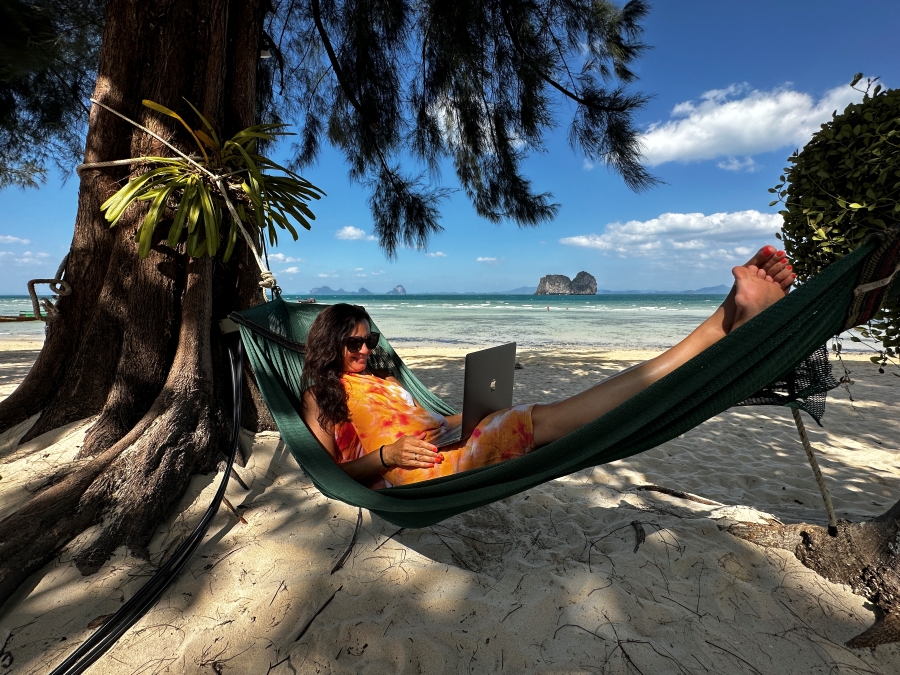 Katarina Stoltz Life Coach and Therapist on her laptop laying in a hammock on the beach in Thailand