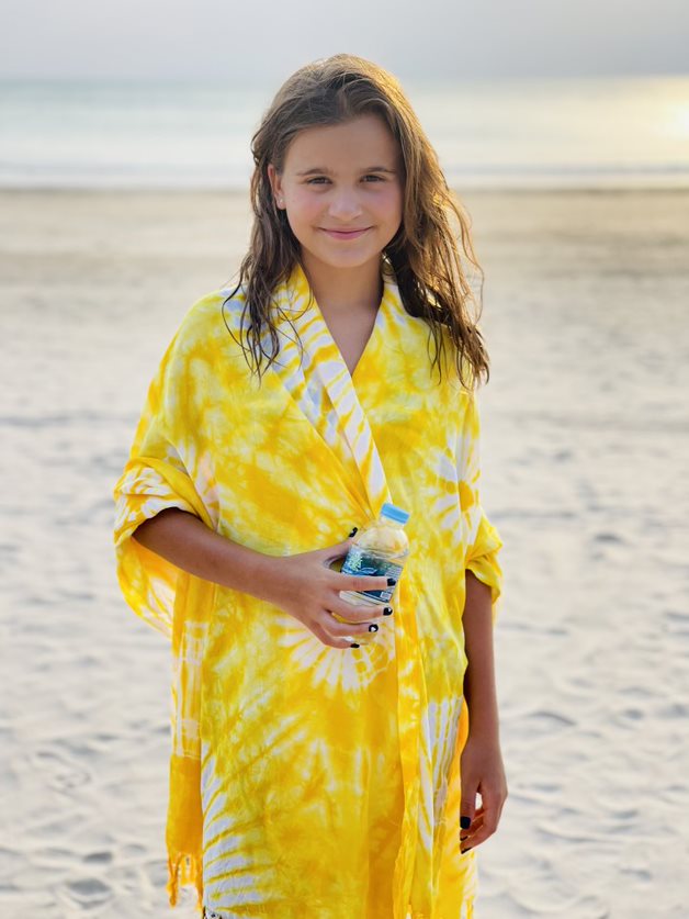 Katarina Stoltz's daughter on the beach in Thailand wearing a bright yellow robe