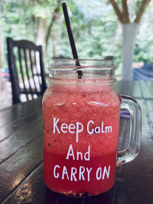 Red smoothie in a glass reading keep calm and carry on on a table in Thailand