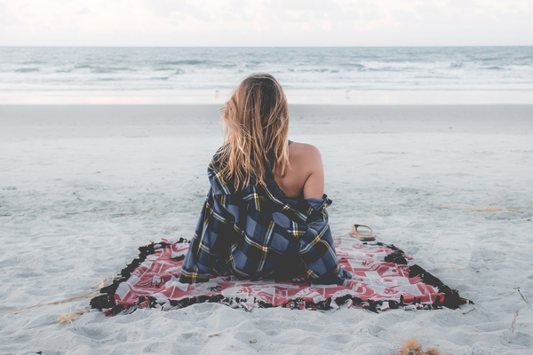 woman sitting on beach who has learnt to make time for herself to find what she has been longing for