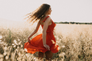 Woman in red dress dancing in field finding meaning in life