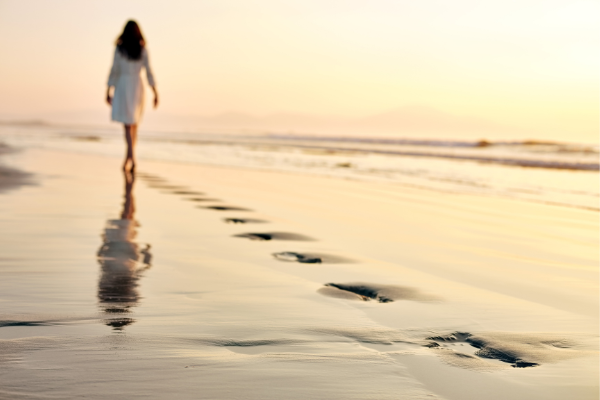 Woman walking along the beach taking time to slow down and get clear on what she really wants.